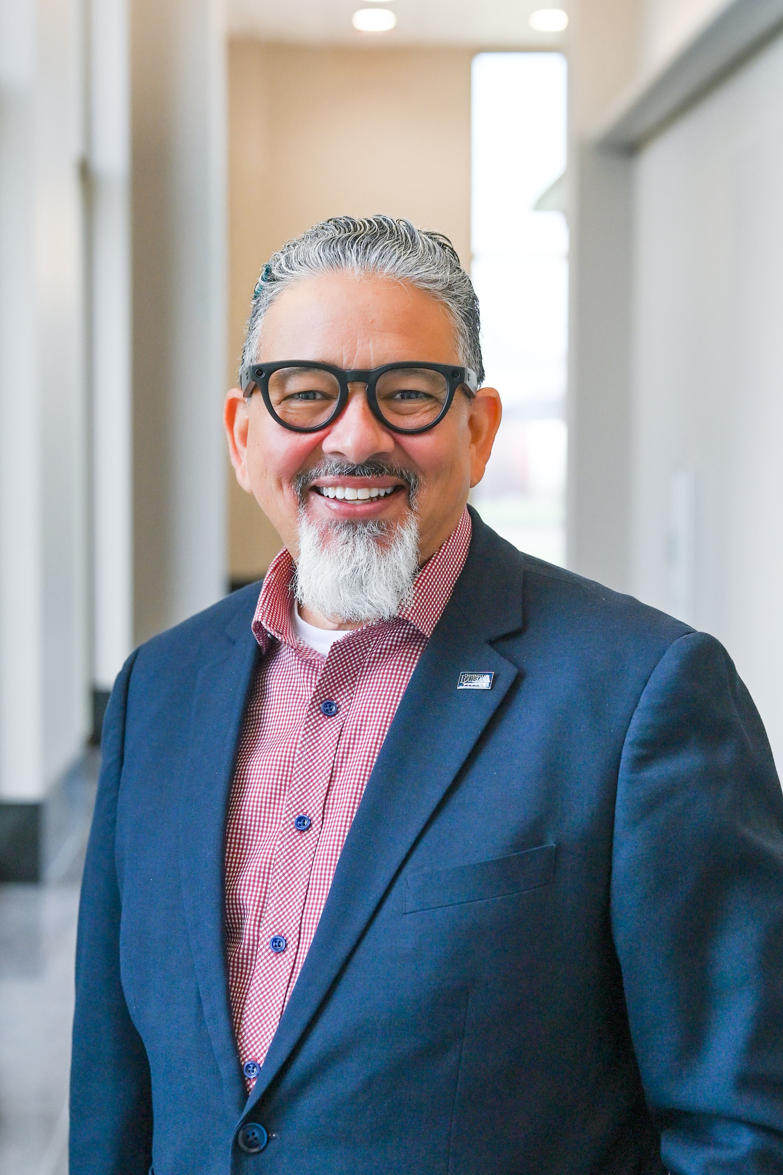 UL System President, Rick Gallot, Ph.D., J.D. wearing a red button down shirt and navy jacket
