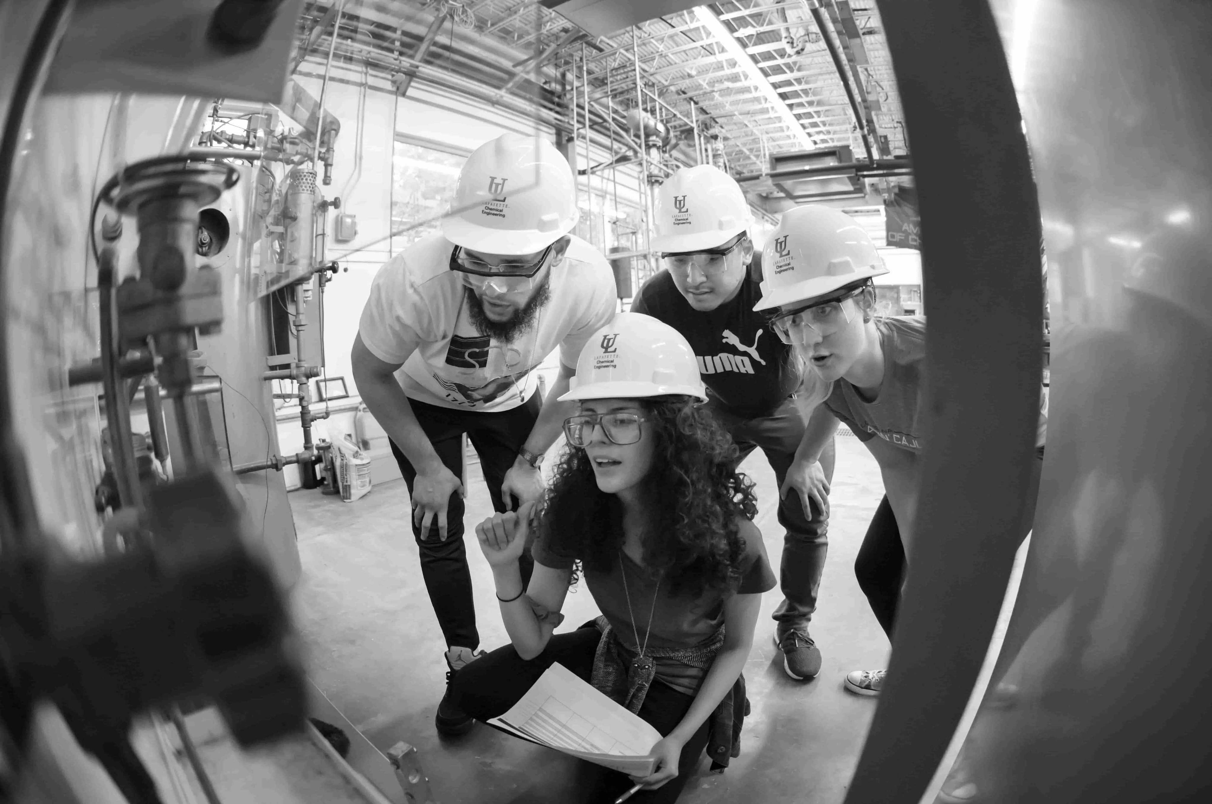 Three individuals with hard hats inspecting device.
